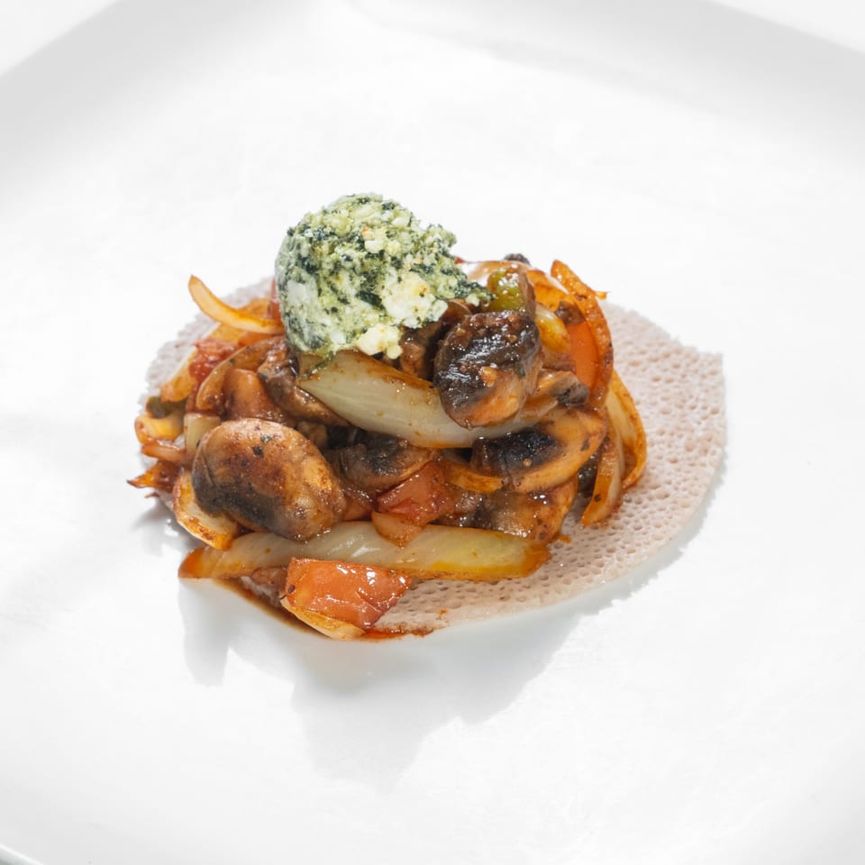 Mushroom ingudai tibs with vegetables on injera.