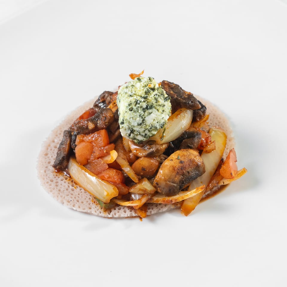Sautéed mushrooms, tomatoes, onions, and potatoes topped with herb cheese on a spongy flatbread.