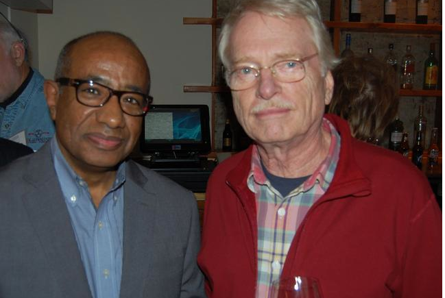 Two men posing for a picture with wine.