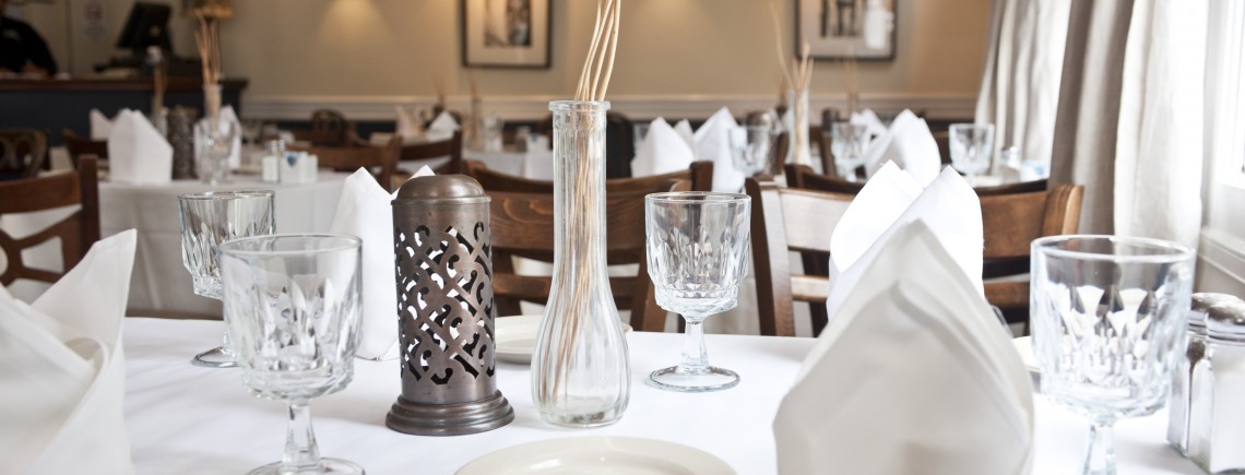 A table set with white plates and silverware.