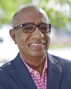 A man in glasses and a suit smiling.