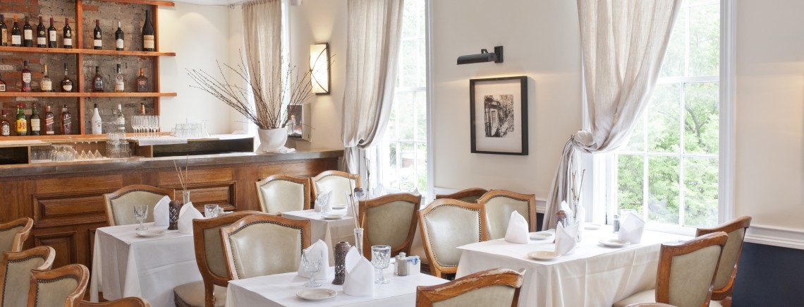 A restaurant with white tables and chairs, and drapes.