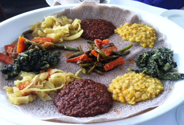 A traditional Ethiopian food platter with various stews and vegetables.