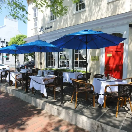 Outdoor cafe with blue umbrellas and tables.