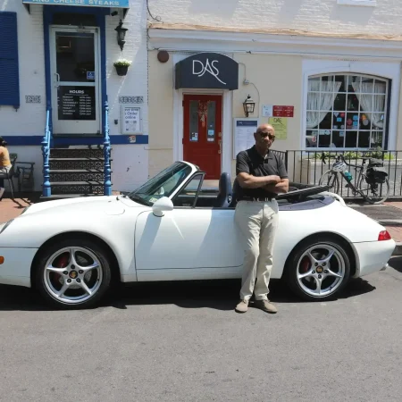 Man standing by a white convertible car.